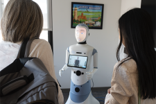 Two women, seen from behind, look at a human-like robot.